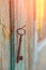 A vintage rusty key hangs on a nail on the wall of an old house, at dawn