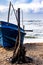 A vintage sailing vessel rests on the sandy shore of an idyllic ocean beach