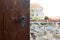 Vintage scratched door knob of a brown wooden door against a city panorama