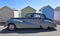 Vintage Silver and Black Armstrong Siddeley Motor Car parked in front of beach Huts.