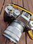 Vintage silver and black Fujifilm camera with brown leather strap on wooden table. Copy space for text. Antique, photography