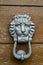 Vintage silver metal doorknob knocker gong on an old wooden door