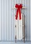 Vintage sled decorated with a red Christmas bow leaning against a wall