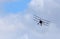 Vintage  Sopwith Triplane in flight with clouds and blue sky.