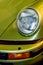 Vintage sports car headlight. Lime green motor vehicle close-up