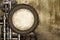 Vintage steampunk backdrop with round frame, pipes on stucco wall. Open space with concrete wall and pipelines. Copy space for