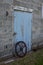 Vintage steel packer wheel in front of a blue antique barn door