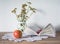 Vintage still life with book, glasses, apple and vase with flowers on doily