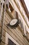 Vintage street clock on the wall of a building, with metal forged decoration.