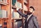 Vintage style and fashion. Bearded man in expensive suit in his cabinet. Professor stands in big library and holds book