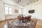 Vintage style office with rectangular wooden meeting table with wooden chairs upholstered in brown leather on a brown carpet and