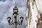 Vintage style street light across blue sky with clouds.