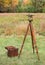 Vintage Surveyors Level (Transit, Theodolite) with wooden Tripod and Case in a field.