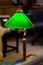 Vintage switched on green lamp on desk in reading room