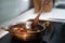 vintage textured copper cooking pot on kitchen with male hand cooking on stove vegetables with meat