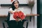 Vintage toned image of attractive young Asian woman in Santa hats holding a bouquet of red roses in office.