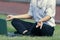 Vintage toned image of relaxed young Asian business man with laptop doing yoga position on the field.