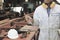 Vintage toned image of young carpenter in white safety uniform holding a pencil in hands in wood workshop background. Industrial c