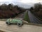 Vintage toy racing car, green worn paint close up, seen from above a main road blurred background