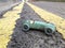 Vintage toy racing car, taken on a real road background showing double yellow lines going into the distance, diagonal perspective