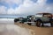 vintage vehicle collection on pristine beach, with waves rolling in