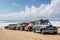 vintage vehicle collection on pristine beach, with waves rolling in