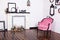 Vintage velor armchair, in a bright room and an artificial fireplace. Interior attic with wooden white walls. Picture frames on th