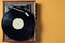 Vintage vinyl turntable with vinyl plate on a yellow pastel background. Entertainment 70s. Listen to music.