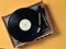 Vintage vinyl turntable with vinyl plate on a yellow pastel background. Listen to music. Top view.