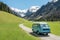 Vintage VW Bully camping car driving on mountain valley road