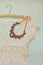 Vintage white crochet lace top with antique necklace on wooden background