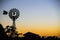 Vintage windmill silhouette against sunset. Silhouette of house, village, trees.