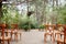Vintage wooden arch wtih red and pink roses - outdoor wedding ceremony location in coniferous forest wtih classic bentwood chairs
