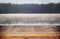 vintage wooden board table in front of abstract photo of misty and foggy lake at morning/evening.