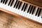 Vintage wooden piano. Keys in the foreground, wooden floor with text space in the blurry background