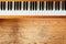 Vintage wooden piano. Keys in the foreground, wooden floor with text space in the blurry background