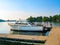 Vintage wooden sea skiff boat with an American flag on the back moored at a dock in a lake with reflection an bouys and trees on