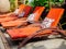 Vintage wooden sunbed with orange pad and pillow near the garden on sunny day