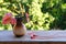 On a vintage wooden table are small red wired headphones, there is a ceramic vase with autumn leaves on a blurred background with