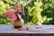 On a vintage wooden table are small red wired headphones, there is a ceramic vase with autumn leaves on a blurred background with