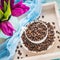 Vintage wooden tray with porcelain cup full of coffee beans and pink flowers on shabby chic mint background, top view