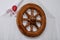 Vintage wooden wheel from cart as decor on the wall. Embroidered canvas with flowers. People`s needlework