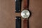 Vintage wristwatch on a brown leather background. Classic watch straps.