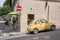 Vintage yellow car parked in a city street corner, illuminated by the warm sunlight