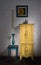 Vintage yellow cupboard, framed painting, blue candlestick and small table