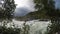 Violent rapid river waterfall during flood in late summer with dense forest