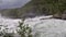 Violent rapid river waterfall during flood in late summer with dense forest, slow motion