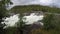 Violent rapid river waterfall during flood in late summer with dense forest, slow motion