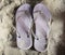 Violet beach slippers on sandy beach, summer