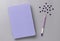 violet blank notebook, pencil and stars confetti on gray desk